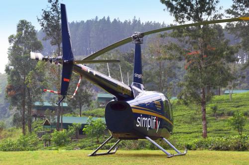 a blue and yellow helicopter sitting on the grass at Madulkelle Tea and Eco Lodge in Kandy