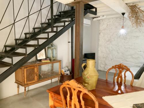 a dining room with a wooden table and a spiral staircase at La Grulla Gris in Perales del Puerto