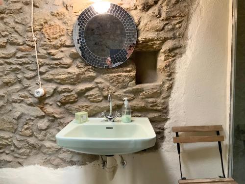 a bathroom with a sink and a mirror on a stone wall at La Grulla Gris in Perales del Puerto