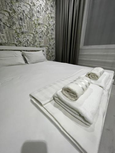 - un lit blanc avec des serviettes dans l'établissement Двухкомнатная квартира, à Aksay