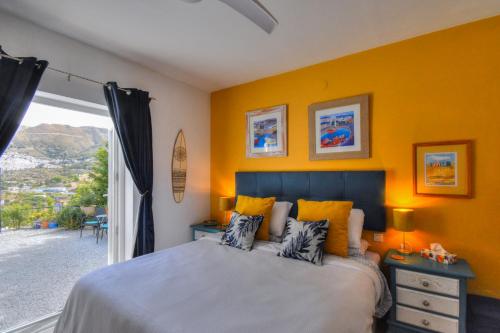 a bedroom with a bed with yellow walls and a window at Casa Vista Maroma in Málaga