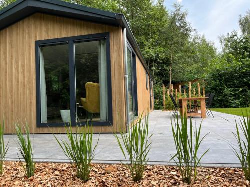 a tiny house with a large window in a garden at Landzicht Natuur Rust en Ruimte in Oosterwolde