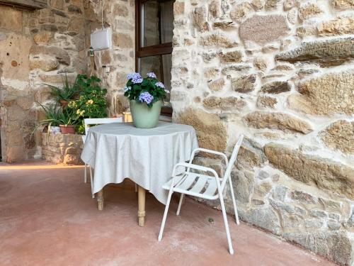 a table with a vase of flowers and two chairs at La Grulla Gris in Perales del Puerto