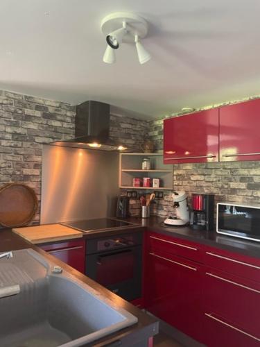 - une cuisine avec des placards rouges et un évier dans l'établissement La Parenthèse gîte à la campagne, à Fougerolles