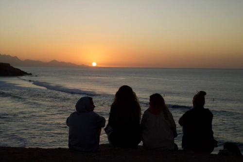 a group of people sitting on the beach watching the sunset at Studio De Ziutek in La Pared