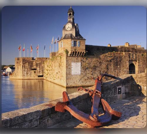 a building with a clock tower next to the water at Cœur de Concarneau, appartement entier, proche centre, corniche et plage avec parking in Concarneau