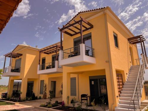 a large yellow house with two balconies on it at Nicolas Luxury Suites in Kourouta
