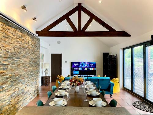 a dining room with a table and a brick wall at 6 Bedroom Bungalow Ascot Racecourse LegoLand Windsor Castle 75" TV in Ascot