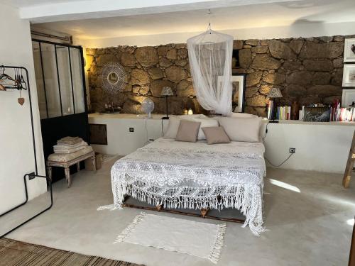 une chambre avec un lit et un mur en pierre dans l'établissement Maison typique Corse écologique, à Coti-Chiavari