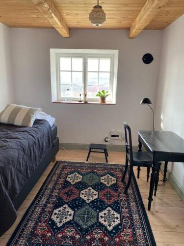 1 dormitorio con cama, mesa y alfombra en 10 min från Malmö/Lund en Staffanstorp