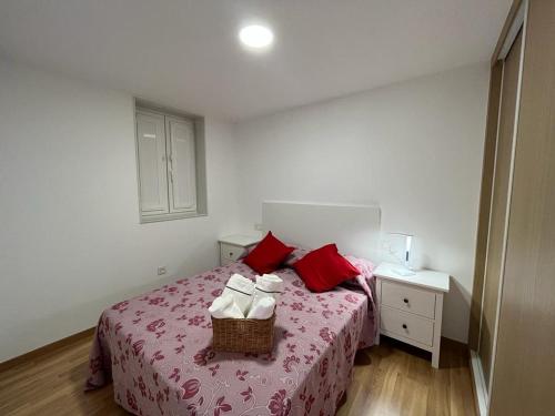 a bedroom with a bed with red pillows and a basket on it at Apartamento Gallaecia Lux in Santiago de Compostela