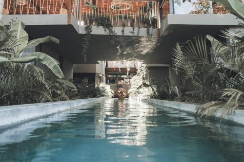 a person standing in a swimming pool next to a building at Siwa Tulum in Tulum