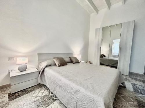 a white bedroom with a bed and a mirror at Tuna House in Carloforte