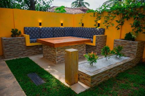 a patio with a wooden table and a yellow wall at Woodnest Saayoo Resort in Negombo