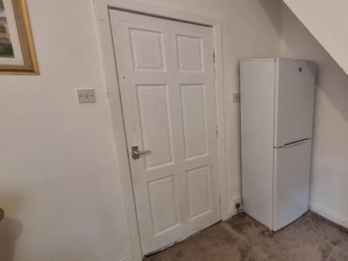 a white door in a room with a refrigerator at 4 Bedroom Spacious House Perfect for Family & Business Short Long-Term Stays Easy Access to Manchester, Oldham, Bury in Rochdale