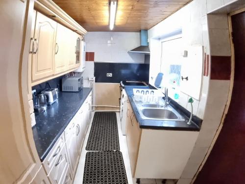 a small kitchen with white cabinets and a sink at 4 Bedroom Spacious House Perfect for Family & Business Short Long-Term Stays Easy Access to Manchester, Oldham, Bury in Rochdale