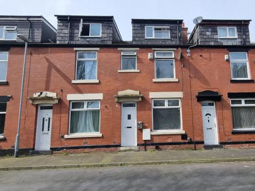 a red brick building with white doors and windows at 4 Bedroom Spacious House Perfect for Family & Business Short Long-Term Stays Easy Access to Manchester, Oldham, Bury in Rochdale