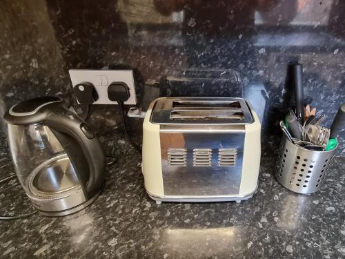 a toaster sitting on a counter next to a tea pot at 4 Bedroom Spacious House Perfect for Family & Business Short Long-Term Stays Easy Access to Manchester, Oldham, Bury in Rochdale