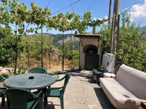 un patio con mesa, sofá y chimenea en Casa nella Natura en Caramanico Terme