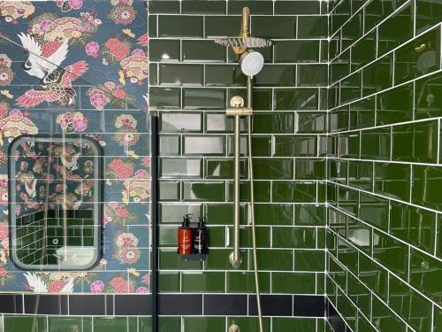 a bathroom with a green tiled wall with a mirror at The Secret Nook in Maryport