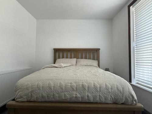 Bett in einem weißen Schlafzimmer mit Fenster in der Unterkunft The Secret Nook in Maryport