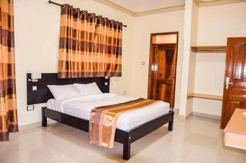 a bedroom with a bed in a room with a window at Ubuntu Palace Hotel in Kampala