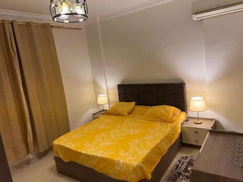 a bedroom with a bed with a yellow comforter and two lamps at Summer vacation flat in Dawwār Ruḩayyim