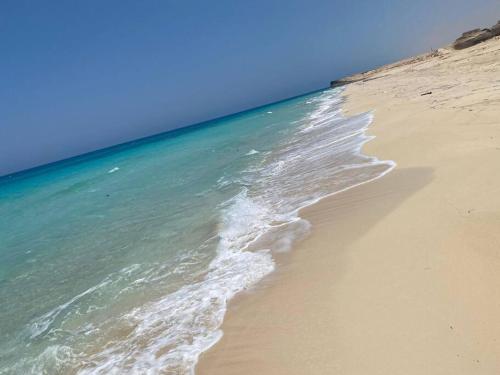 una playa de arena con el océano y el cielo en Summer vacation flat en Dawwār Ruḩayyim