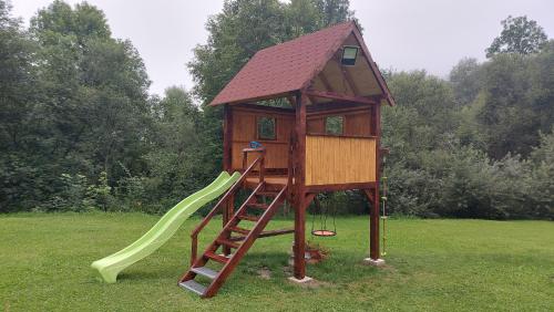 una torre de juegos de madera con un tobogán y una casa de juegos en B&B Emarik, en Podobin