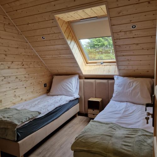 two beds in a small room with a window at Przystań nad Sanem in Tyrawa Solna