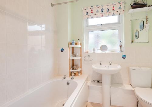 a bathroom with a tub and a sink and a toilet at Forget-me-not Bungalow in Seaton
