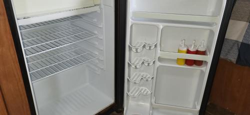 an empty refrigerator with its door open and drinks inside at Moceanset Getaways-Beautiful Ocean, Mountain & Sunset Views, "Camping Experience" in Dingwall