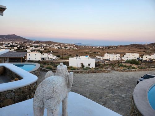 a statue of a camel standing on a balcony overlooking a city at Diamond Of Mykonos in Ano Mera