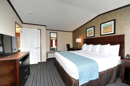 a hotel room with a large bed and a flat screen tv at Instalodge Hotel and Suites Karnes City in Karnes City