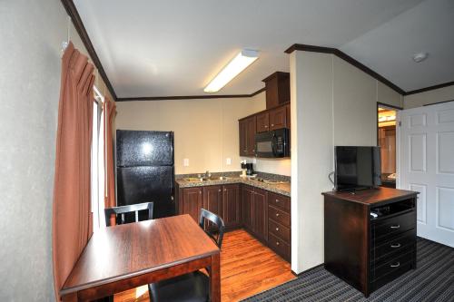 a kitchen with a wooden table and a black refrigerator at Instalodge Hotel and Suites Karnes City in Karnes City