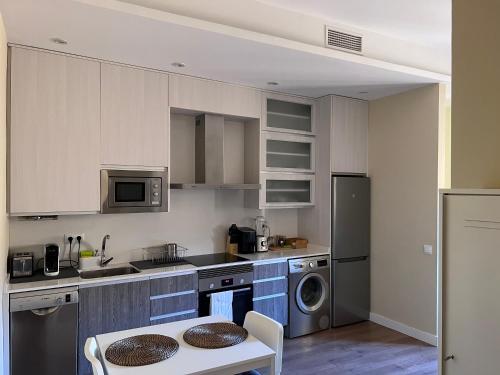 cocina con armarios blancos, mesa y fregadero en Apartment in monumental square Madrid Center, en Madrid