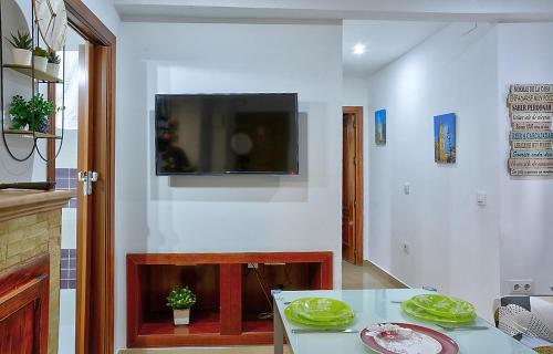 sala de estar con mesa y TV en la pared en Apartamento Muralla, en Sevilla