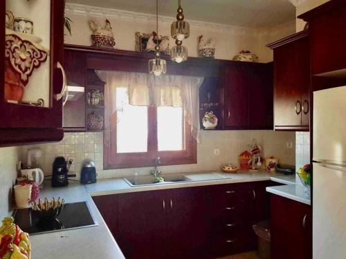 cocina con armarios rojos, ventana y fregadero en Nikitas Luxury House, en Karpathos
