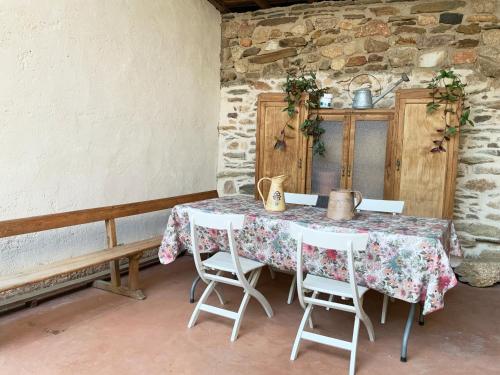 a table and chairs in a room with a stone wall at La Grulla Dorada in Perales del Puerto