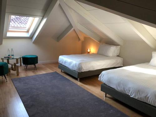 Schlafzimmer im Dachgeschoss mit 2 Betten und einem Tisch in der Unterkunft Casa Riviera by Corte Gondina in La Morra