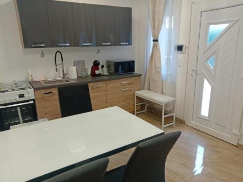 eine Küche mit einem weißen Tisch und Stühlen sowie einer Tür in der Unterkunft Hangjegy Apartman in Debrecen