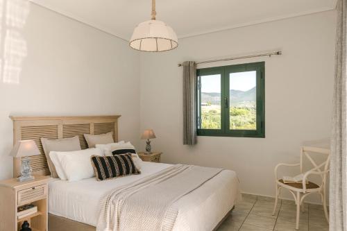 Habitación blanca con cama y ventana en Seaspray Villa Kefaloniaprivatevillas, en Cefalonia