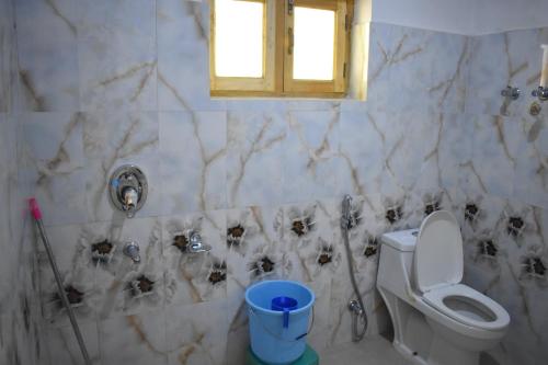 a bathroom with a toilet and skulls on the wall at Kushu Guest House in Leh