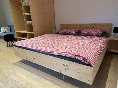 a wooden bed with a red and white checkered blanket at Schlossquelle Königsdorf in Königsdorf