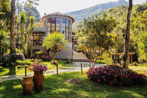 una casa con flores delante en Quinta da Torre 7 suítes Cachoeira SPA aquecido en Petrópolis