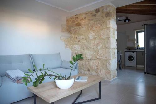 ein Wohnzimmer mit einem Sofa und einem Tisch mit einer Pflanze in der Unterkunft Myra city House in Chania