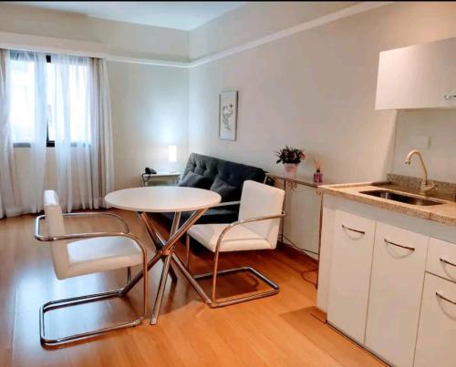 a kitchen and a living room with a table and chairs at Flat Alameda Lorena - Prédio Ninety - Jardim Paulista in Sao Paulo