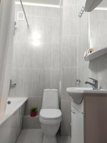 a white bathroom with a toilet and a sink at В Астане новая комфортная квартира у реки и парка in Kirovo