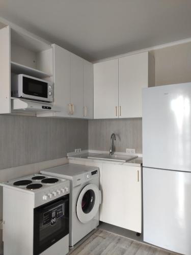 a kitchen with a washing machine and a microwave at В Астане новая комфортная квартира у реки и парка in Kirovo