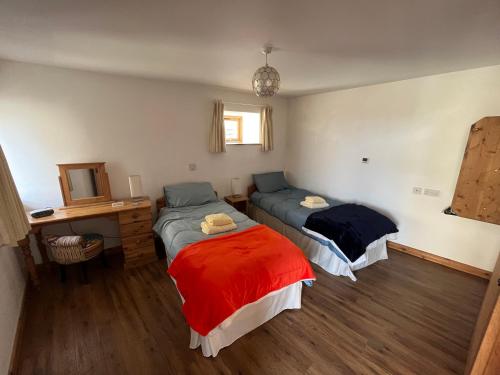 ein Schlafzimmer mit zwei Betten und einem Schreibtisch und einem Spiegel in der Unterkunft The Corn Store in Porthtowan